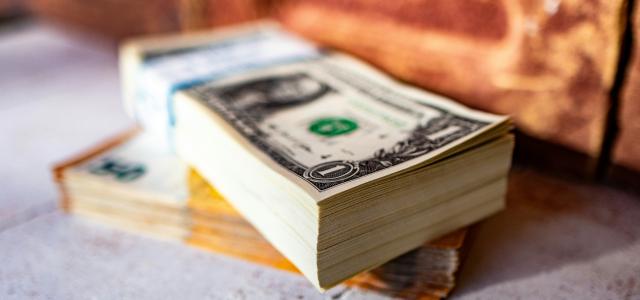 a stack of money sitting on top of a sidewalk by Marek Studzinski courtesy of Unsplash.